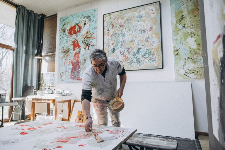 Künstler arbeitet in seinem Atelier an einem farbenfrohen abstrakten Gemälde.