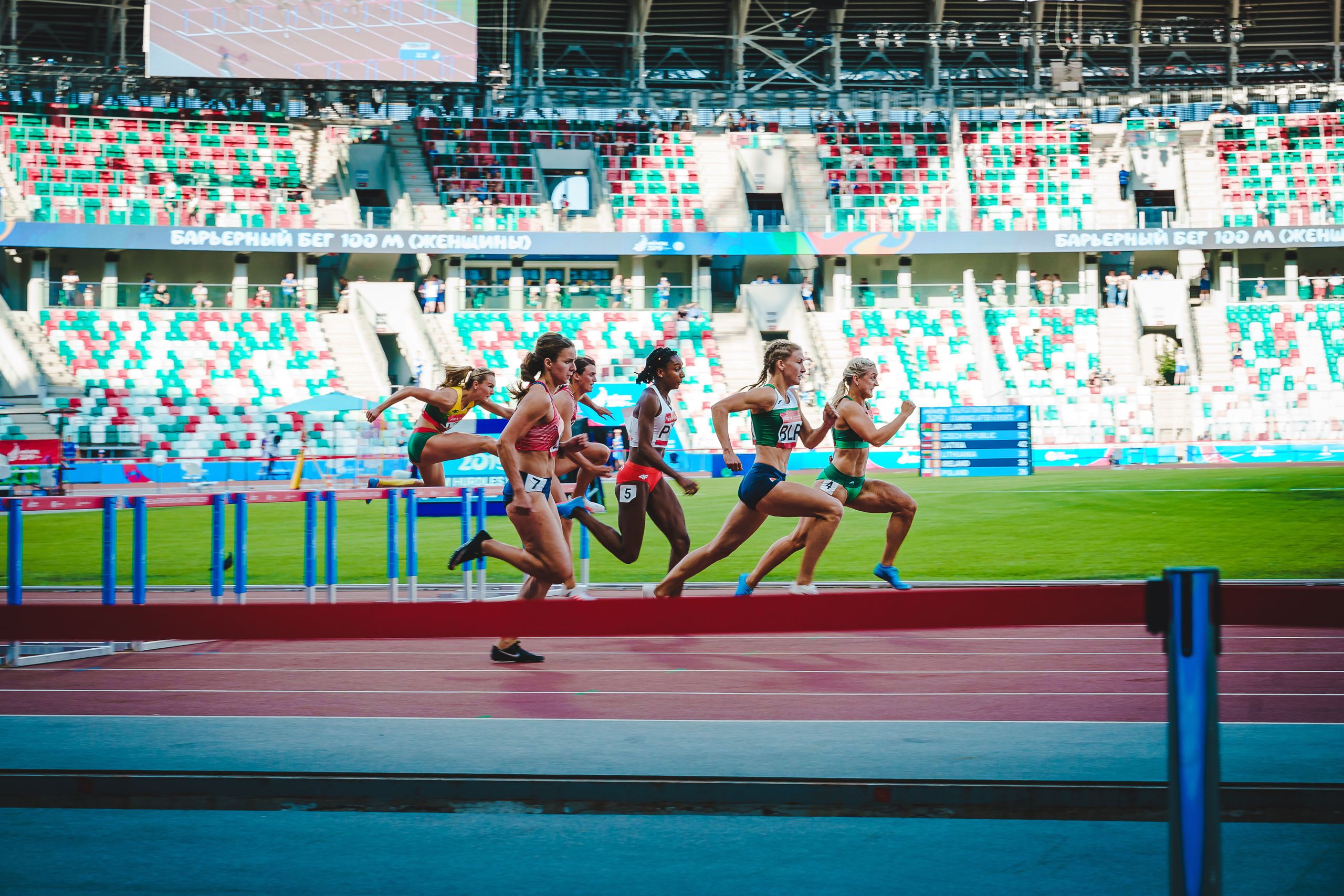 Athletinnen bei einem intensiven Hürdenlauf im Stadion.